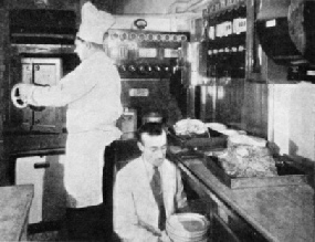 COOKING BY ELECTRICITY. The chef and his assistant in the wonderful all-electric kitchen